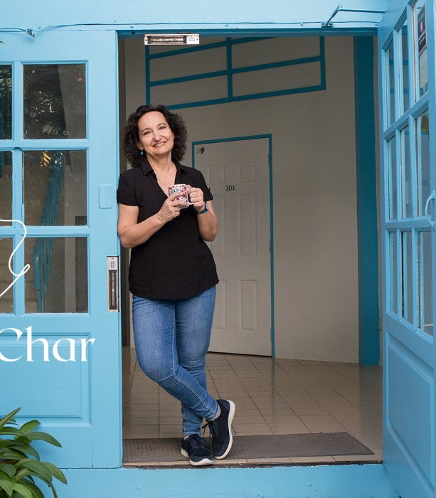 Inga standing in a blue doorway with a cup