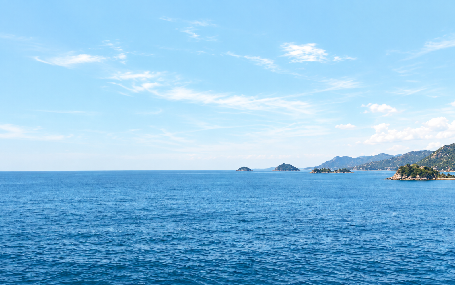 Open sea and a distant island beneath a wide sky