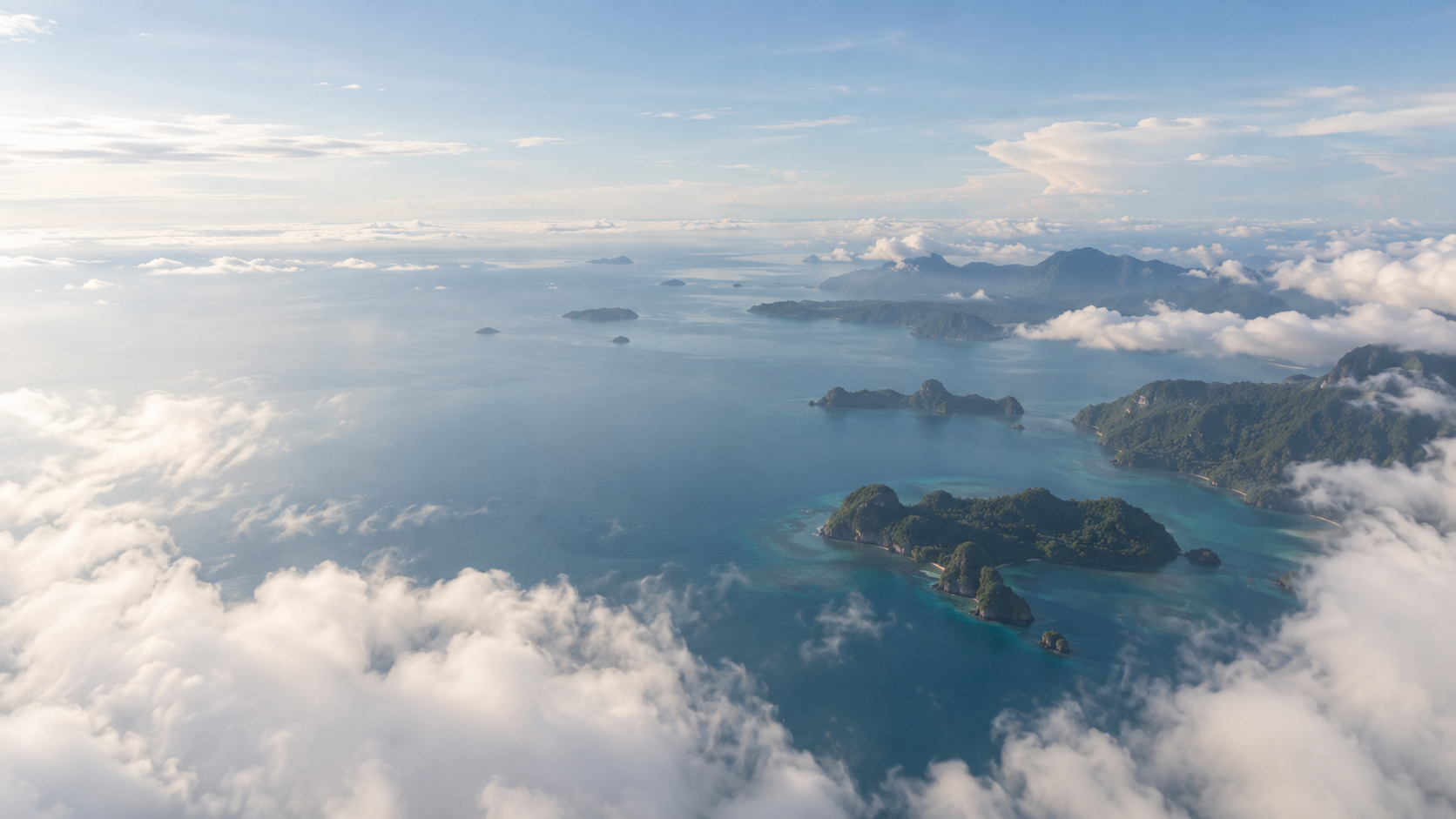 Forested islands emerging through soft clouds beneath an open blue sky